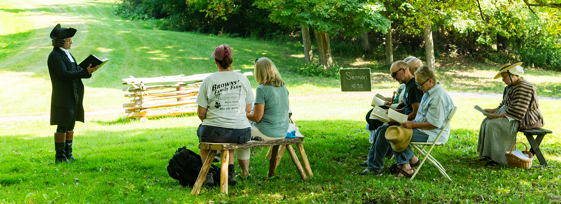 people sitting in chairs watching person read from a book